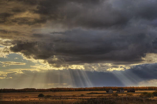 Sun Rays Through Clouds Over Three Old Grain Bins, Rural Alberta