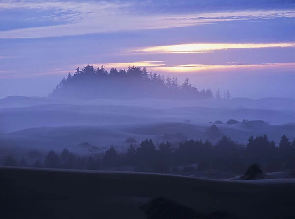 The Sun Sinks Low At Sunset With A Fog Covered Landscape; Lakeside, Oregon, United