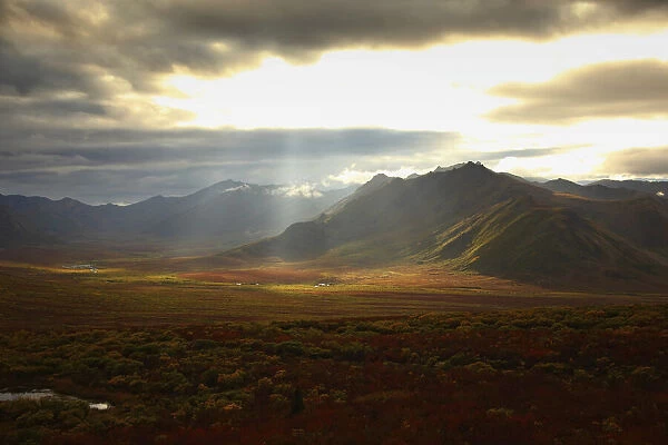 Sunlight Filtering Through Storm Clouds Illuminating The Fall Colours And Mountains Of The Cloudy Range Along The Demspter Highway, Yukon