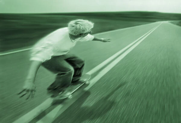 Teenager skateboarding down road