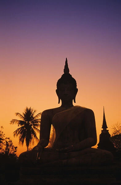 Thailand, Sukhothai, Wat Mahathat At Sunset, Silhouetted Buddha Statue, Purple And Orange Sky