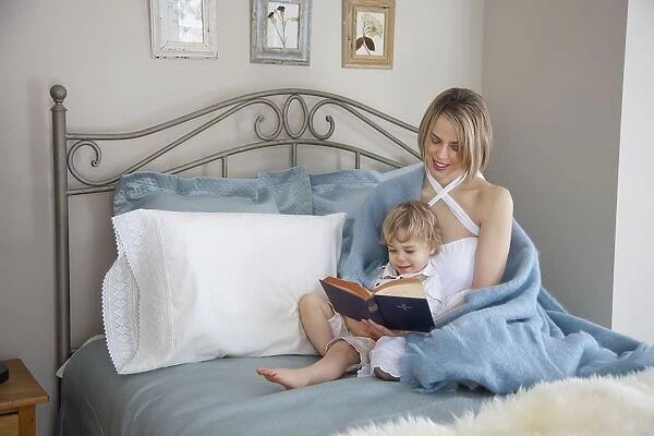 Toddler And Mother In Bed Reading; Jordan, Ontario, Canada