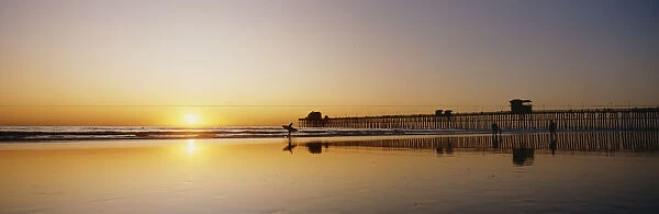 USA, Reflections On Beach; California, Oceanside Pier And Surfers Silhouetted Against Sunset