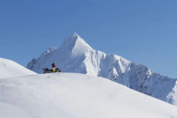 Woman Scoping Her Route Backcountry Skiing By Snowmobile In The Chugach Mountains Late Winter, Southcentral Alaska