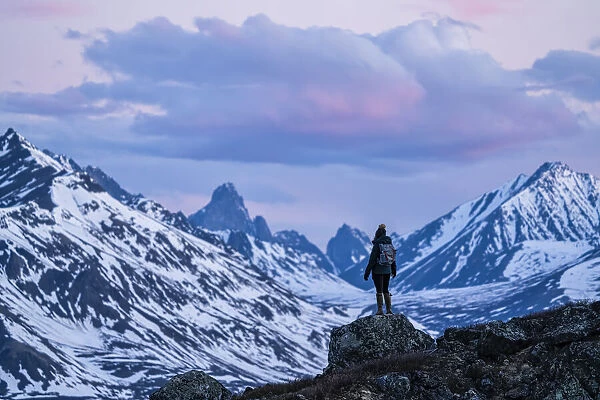 Woman standing on a rock overlooking the Klondike Valley along the Dempster Highway, Yukon, Canada
