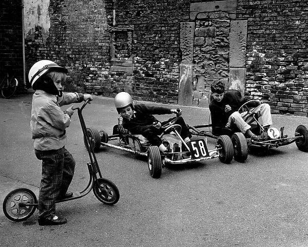 Children play on their scooter and go-karts. Circa 1960