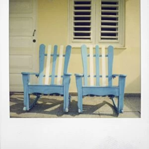 Polaroid of two chairs painted white and blue on porch of traditional house