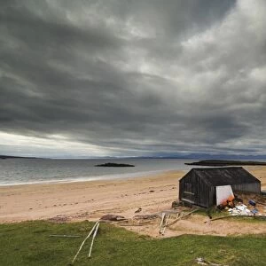 Stormy sky with fishermans hut and net drying poles, Redpoint beach