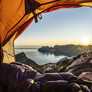 Warm lights of sunrise view from the inside of hikers tent, Senja island