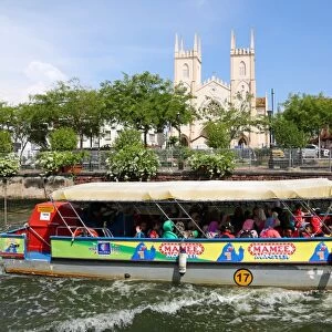 Church of St. Francis Xavier and a tourist sightseeing boat on the Sungai Melaka river in Malacca, Malaysia