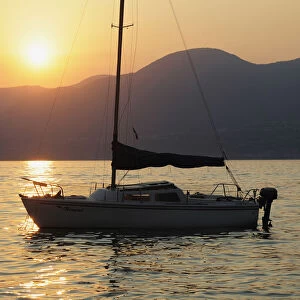 Italy, Veneto, Lake Garda, sunset over lake with boat