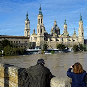 A couple observes the River Ebro close to overflowing, following heavy rains