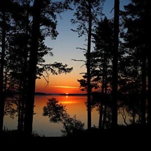 Sun rises behind a lake near the town of Vileika