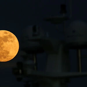 A supermoon full moon rises behind the antennae domes on a motor yacht in Pieta