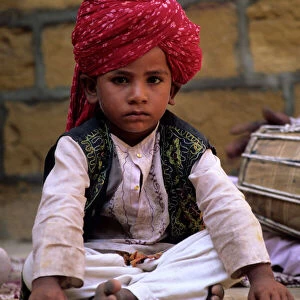 India, Rajasthan, Jaisalmer. Boy dancer rests between songs at entrance to Jaisalmer Fort