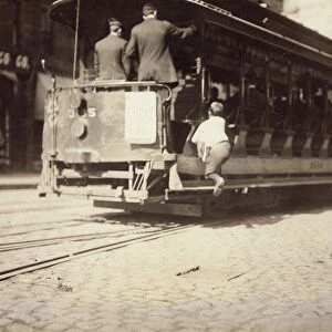 BOSTON: NEWSBOY, 1909. A newsboy flipping cars, on a trolley in Boston, Massachusetts