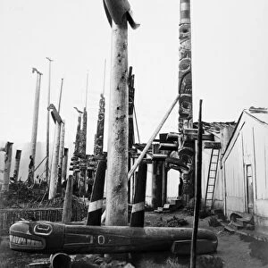 CANADA: HAIDA TOTEM POLES. Totem poles in front of houses in the Haida village of Haina