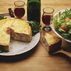 Ham and egg tart, one slice removed, a plate of mixed salad, and two glasses and a bottle of red wine