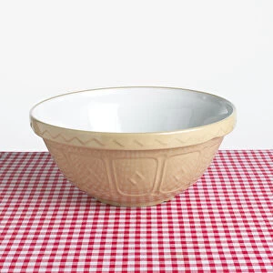 Old fashioned mixing bowl on red and white checked tablecloth, close-up