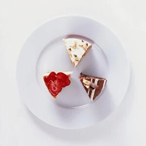Slices of carrot cake, chocolate fudge cake, and strawberry cheesecake on white plate