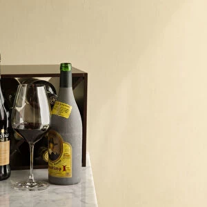 Wine rack with bottles of Spanish wine and sherry on marble table next to large glass of red wine