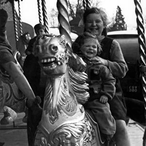 Two girls sitting on a horse on the merry-go-round at the Funfair
