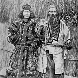 Ainu Couple outside the traditional Ainu home of a reed thatched hut