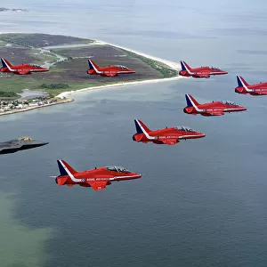 A F-22 Raptor flies in formation with the Royal Air Force Aerobatic Team, The Red Arrows
