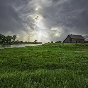 Abandoned barn with storm clouds converging overhead