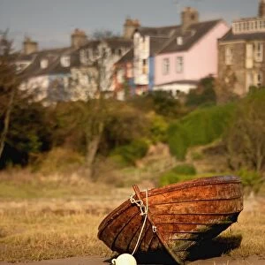 Alnmouth, Northumberland, England; An Abandoned, Rusted Boat Sitting On Land With Houses In The Background