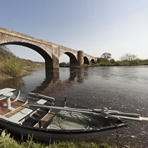 A Boat Along The Shoreline Beside A Bridge In River Tweed; Scottish Borders Scotland
