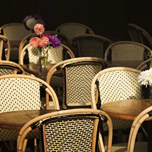 A Bouquet Of Flowers Amongst Empty Parisian Bistro Chairs And Tables; Paris, France