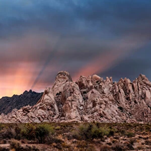 Crepuscular rays at sunset behind rock formations in the Mojave Desert, Kelso, California, USA