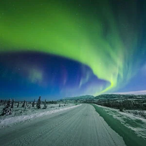 The Moon And Aurora Shine In The Night Sky Over A Snow Covered Richardson Highway South Of Delta Junction; Alaska, United States Of America