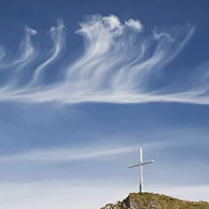 Mountain Peak With A Cross On Top Against A Blue Sky With Clouds; Fussen, Germany