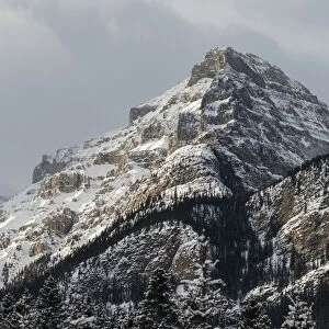 Rugged Mountain Peak With Snow Under A Cloudy Sky; Lake Louise, Alberta, Canada