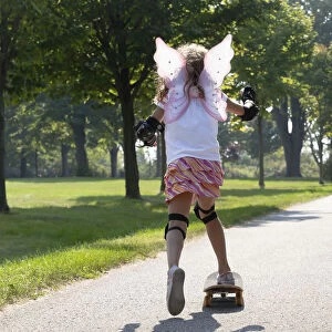 Young Girl Skateboarding While Wearing Fairy Wings; Whitby Ontario Canada