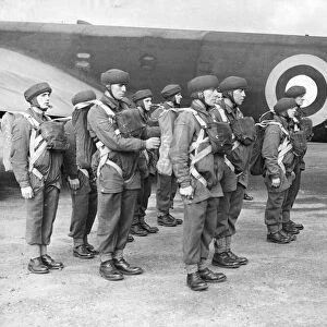 The corporal inspecting the parachute equipment of British parachutists before they enter