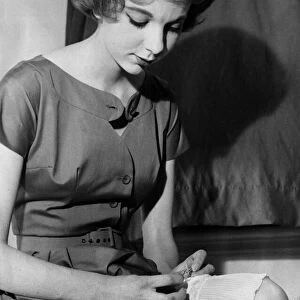 Film actress Anna Massey sews a special brooch from her mother on one of her frillies for