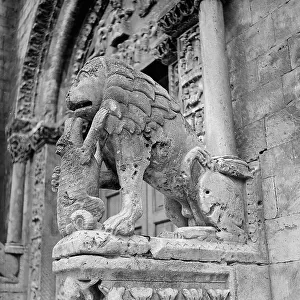 Column-bearing lion to the left of the middle portal of the Cathedral of San Michele, in Bitetto