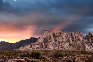 Crepuscular rays at sunset behind rock formations in the Mojave Desert, Kelso, California, USA Crepuscular rays at sunset behind rock formations in the Mojave Desert, Kelso, California, USA
