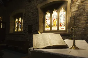 An Open Bible On Display In A Church With Colourful Stained Glass Windows; Bamburgh An Open Bible On Display In A Church With Colourful Stained Glass Windows; Bamburgh