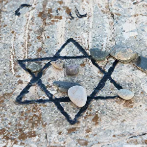 A star of david etched and painted on a rock with stones laying on it A star of david etched and painted on a rock with stones laying on it